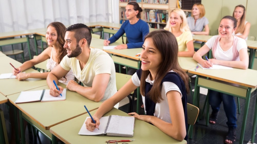 41004839 - group of happy students at their desks in college classroom