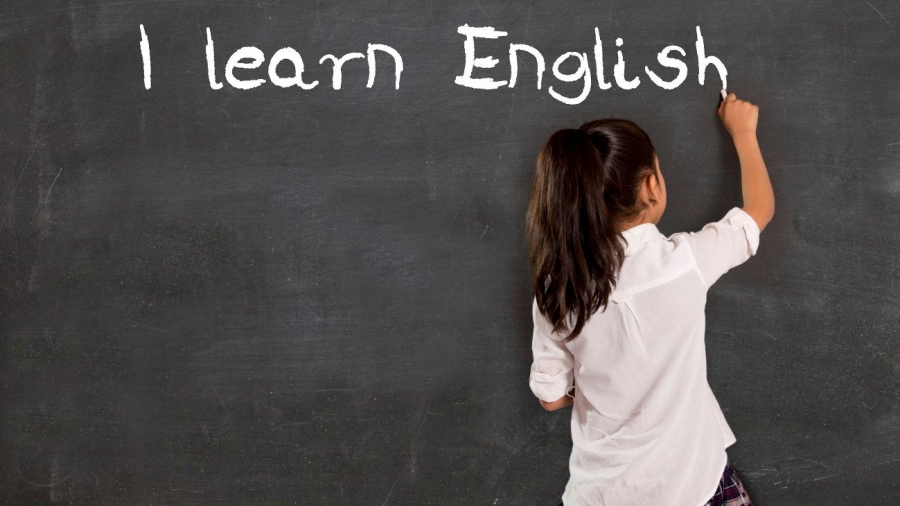 31799113 - sweet little hispanic girl at school lesson with ponytail and uniform writing with chalk on classroom blackboard in english learning , wisdom and successful education concept