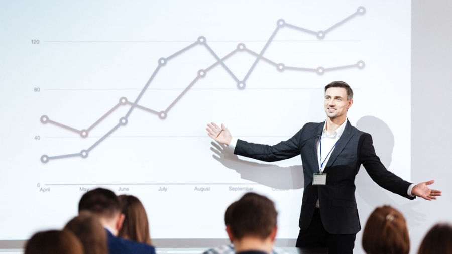 Smiling charismatic speaker giving public presentation in conference hall