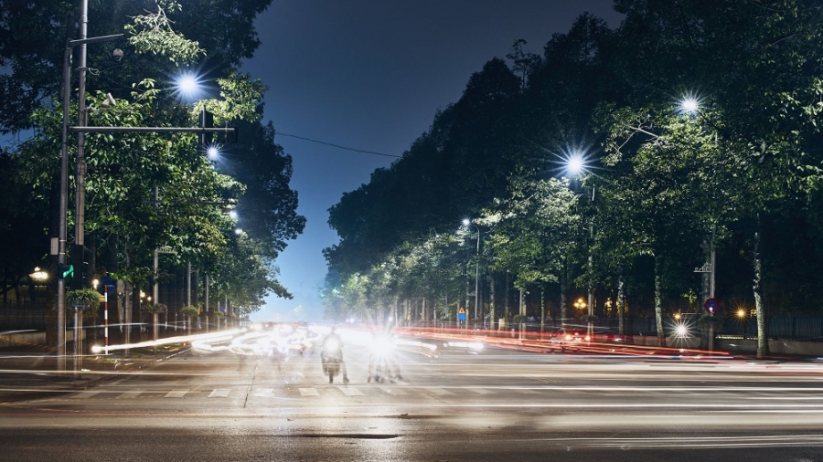 Motorcycles waiting on crossroad. Light trails of traffic in city. Hanoi at night, Vietnam.