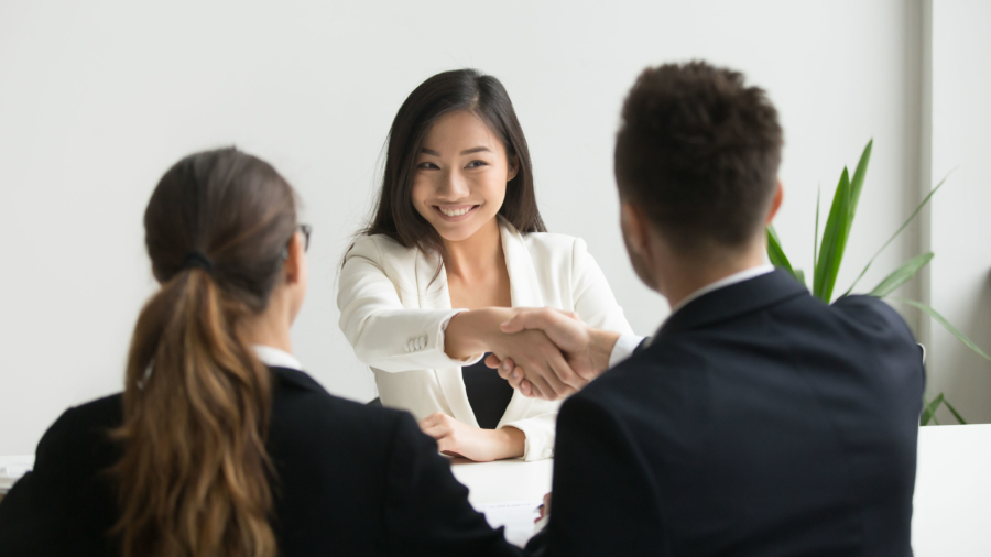 Happy millennial asian applicant getting hired shaking hand of hr, employer handshaking successful smiling chinese candidate congratulating with job interview win offering employment contract concept